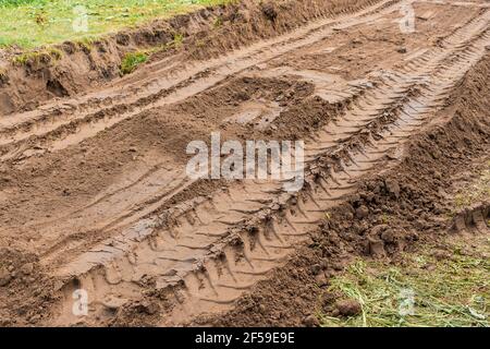 Spuren und Muster von Reifenlaufrädern auf dem Boden des industriellen Transports auf der Baustelle. Stockfoto