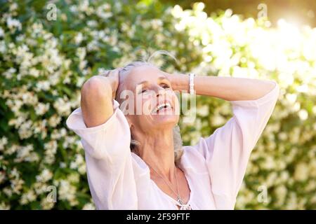 Nahaufnahme Porträt der sorglosen älteren Frau mit Händen in Haare Stockfoto
