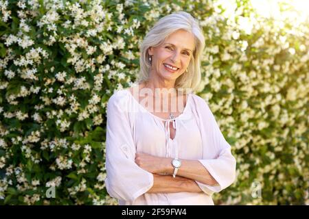 Porträt einer älteren Frau, die lächelt und im Frühling draußen steht Stockfoto