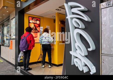 Kunden werden beim Kauf von Lebensmitteln in der amerikanischen multinationalen Fast-Food-Hamburger-Restaurantkette McDonald's und McCafe-Logos in Hongkong gesehen. Stockfoto