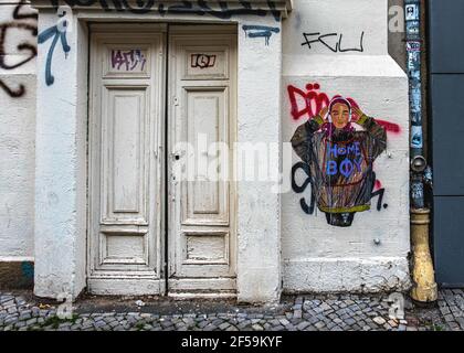 Gebäudedetail, alte Holztür, Aufkleber bedeckt Ablaufrohre Graffiti, Stadtkunst, gepflasterte Bürgersteig, Mitte, Berlin Stockfoto