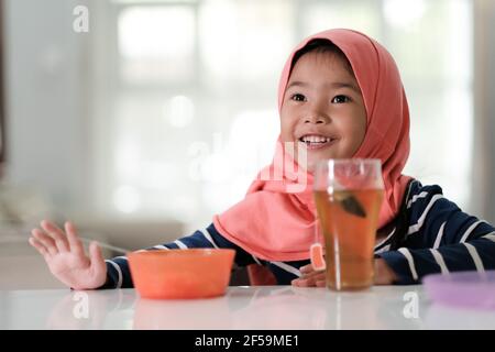 Nahaufnahme des kleinen Mädchens trägt Hijab sitzen in der Küche genießen Frühstück Stockfoto