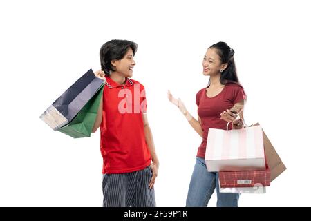 Asiatische junge Männer und Frauen reden einander anguend Beim Halten von Einkaufstaschen Stockfoto