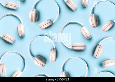 Draufsicht auf kreative Muster aus weißen kabellosen Kopfhörern Auf blauem Hintergrund Stockfoto
