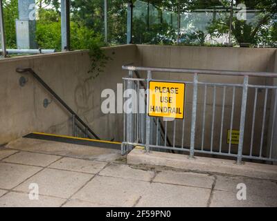 A Bitte benutzen Sie das Handlaufschild auf den Handläufen in einem Treppenhaus, das zu einer Tiefgarage am Einkaufszentrum Mall in Cribbs Causeway in der Nähe von Bristol, England führt. Stockfoto