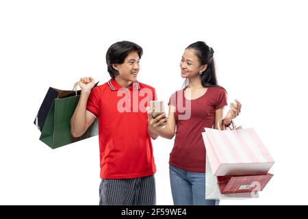 Asiatische junge Männer und Frauen reden einander anguend Beim Halten von Einkaufstaschen Stockfoto