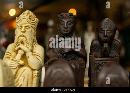 Geschnitzte Schachfiguren aus Holz, Nahaufnahme, kleine Figuren von König, Königin und Bischof in Holzhandschnitzkunst, zwei dunkle und ein weißes Stück Stockfoto