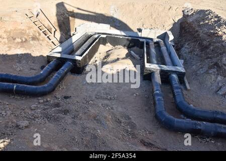 Verlegung von Heizrohren in einem Graben auf der Baustelle. Installation von unterirdischen Sturmsystemen für die Wasserleitung und die Sanitärabwasserkanäle Kaltes und warmes Wasser, Heizung Stockfoto