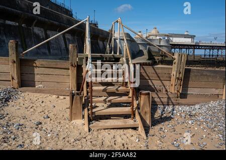 Eine Reihe von Schritten über eine hölzerne Seeverteidigung mit Handschienenbahnen an einem North Norfolk Strand bei Ebbe Stockfoto