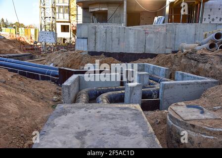 Verlegung von Heizrohren in einem Graben auf der Baustelle. Installation von unterirdischen Sturmsystemen für die Wasserleitung und die Sanitärabwasserkanäle Kaltes und warmes Wasser, Heizung Stockfoto