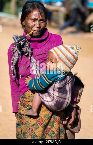 Frau mit traditionellen Gesichts-Tattoo tragen Kind, Minhat, Myanmar Stockfoto