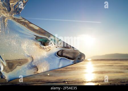 Blick auf den Sonnenuntergang durch das eisige transparente Dreieck auf dem Eis Von L Stockfoto