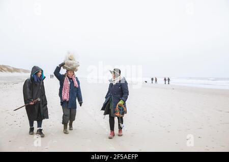 Drei Freunde tragen Müll am Strand entlang der Nordsee in Dänemark Stockfoto