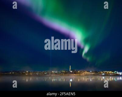 Küstenstadt gegen Nordlichter Stockfoto