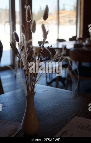 Ein Bouquet von getrockneten Blumen steht in einer Vase darauf Ein Tisch gegen t Stockfoto