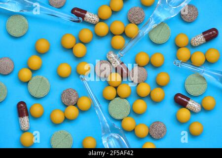 Kapseln, Tabletten, Ampullen und Dragees sind auf einem blauen Backgr verstreut Stockfoto