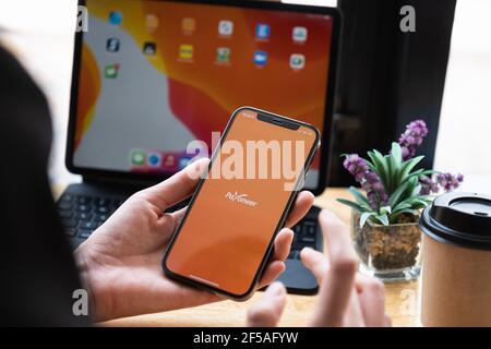 CHIANG MAI, THAILAND - Mar 08, 2021 Frau mit Payoneer auf dem iPhone mit Tablet auf Hintergrund. Payoneer ist ein weltweites Online-Zahlungssystem Stockfoto