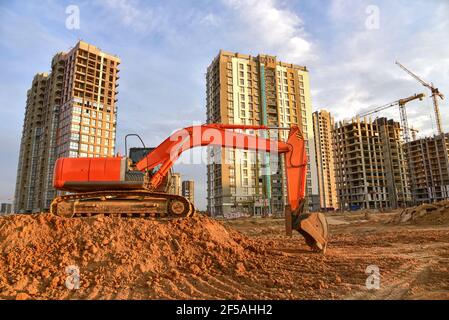 Bagger während der Aushubarbeiten auf der Baustelle auf Sonnenuntergang Hintergrund. Red Backhoe auf der Straße arbeiten. Schwere Baumaschinen für Erdarbeiten. Digger D Stockfoto