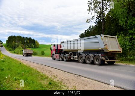 LKW mit Kipper Sattelauflieger transportierte Sand aus dem Steinbruch auf der Fahrt entlang der Autobahn. Moderne Dump Semi-Trailer Heckkipper Lkw-Anhänger Stockfoto