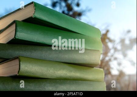 Stapel grüner Bücher. Bücher vor strahlendem Frühlingshimmel Stockfoto