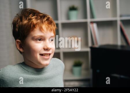 Nahaufnahme Porträt von fröhlichen Sommersprossen Rotschopf Kind Junge sitzt auf Tisch und wegschauen Stockfoto