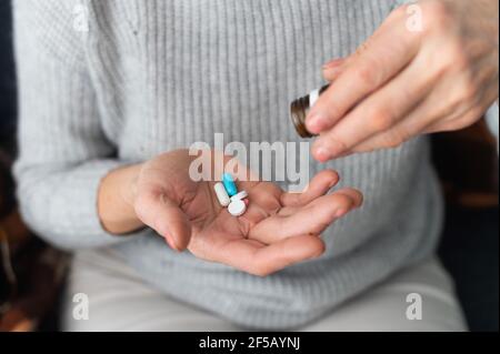 Ältere Frauen, die Vitamine und Nahrungsergänzungsmittel nehmen, um die Immunität zu erhalten, sich um die Gesundheit zu kümmern. Weibliche Handfläche mit verschiedenen Pillen darauf, beschnittenes Foto, kein Gesicht Stockfoto