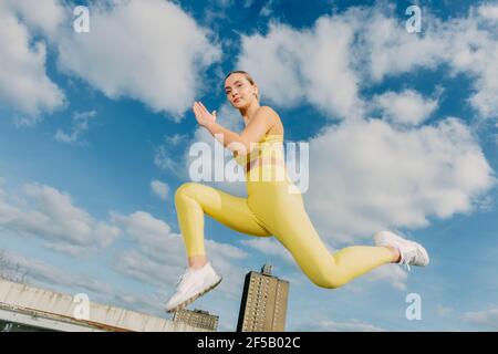 Sportliche Frau in gelber Sportbekleidung in der Luft, springen beim Laufen. Stockfoto