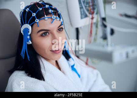 Entspannte dunkelhaarige Frau, die sich dem EEG-Verfahren unterzieht Stockfoto