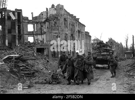 Köln, Deutschland 1945 amerikanische Truppen eskortieren verletzte gefangene deutsche Soldaten, nachdem sie sich während des Zweiten Weltkriegs nach schweren Bombardierungen der Stadt ergeben hatten. Zweiter Weltkrieg. deutsche Niederlage alliierter Sieg Deutschland 1940er Jahre Kapitulation Europa Europäische Geschichte Zerstörung Stockfoto