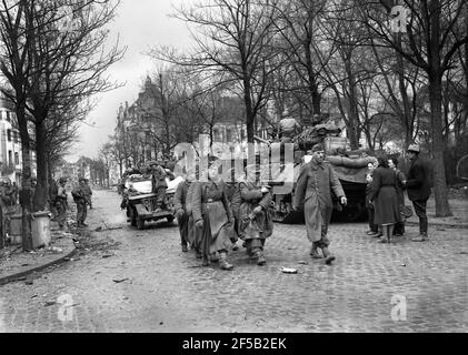 Köln, Deutschland 1945 amerikanische Truppen eskortieren gefangene deutsche Soldaten, nachdem sie sich während des Zweiten Weltkriegs, nach schweren Bombenangriffen auf die Stadt, von Einheimischen beobachtet, ergeben hatten. Zweiter Weltkrieg. deutsche Niederlage alliierter Sieg Deutschland 1940er Jahre Kapitulation Europa Europäische Geschichte Zerstörung Stockfoto