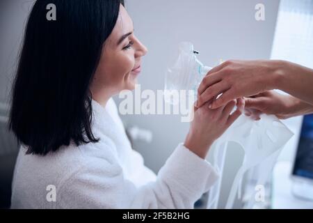 Lächelnd attraktive dunkelhaarige Frau immer zusätzlichen Sauerstoff Stockfoto