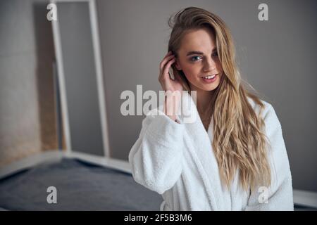 Patient in einem Frottee-Bademantel sitzt in einem Massageraum Stockfoto