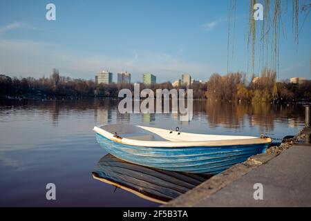 Kleines Ruderboot, das am Ufer auf dem See ruht In einem sehr verschmutzten roten Wasser Stockfoto