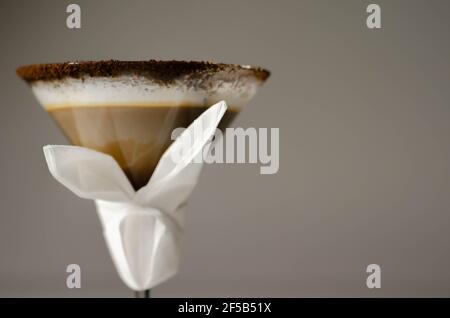 Kaffeecocktail mit nussiger Note mit flauschigem Milchschaum, verziert mit Schokoladenspänen, serviert mit einer Osterhasen-förmigen Serviette, süßem Getränk Stockfoto
