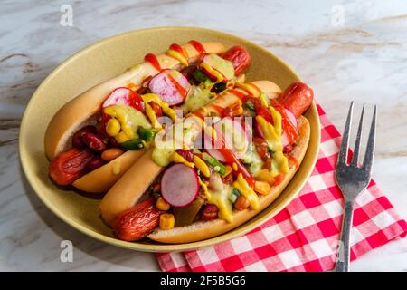 Ausgefallene Chili-Hunde mit Radieschen Senf Ketchup und grün gekrönt Soße auf glutenfreien Brötchen Stockfoto