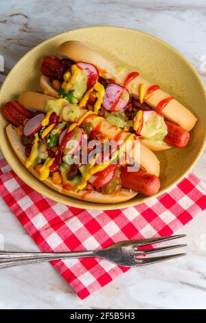 Ausgefallene Chili-Hunde mit Radieschen Senf Ketchup und grün gekrönt Soße auf glutenfreien Brötchen Stockfoto