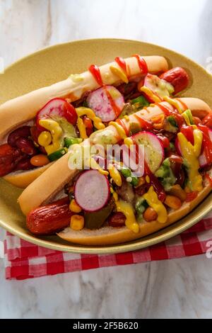 Ausgefallene Chili-Hunde mit Radieschen Senf Ketchup und grün gekrönt Soße auf glutenfreien Brötchen Stockfoto