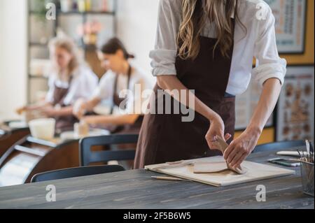 Junge Frauen lernen, mit einem Ton auf einem zu Formen Töpferscheibe während einer Lektion in der Werkstatt im Kunststudio Stockfoto