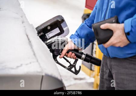 Mann, der die Kraftstoffdüse hält und den Tank des Dieselautos mit Schnee befüllt Stockfoto