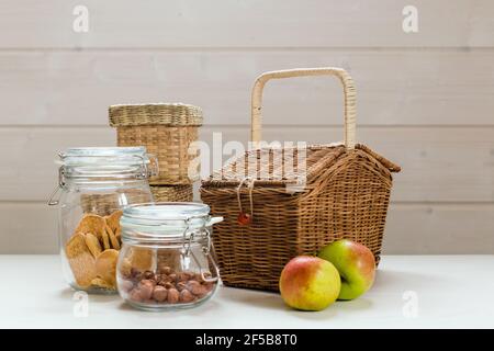 Glasdosen mit Nüssen und Keksen und Äpfeln auf Holztisch, Zero Waste Picknick-Konzept Stockfoto