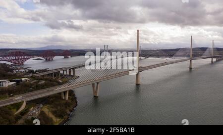 North Queensferry, Schottland, Großbritannien. März 2021, 25th. IM BILD: Bewölkt, windig mit Schauern. Drohnenfotografie Luftaufnahme von oben Blick nach Süden über den Firth of Forth mit den drei Brücken; Queensferry Crossing (Hauptbild), eine Brücke, die die Autobahn M90 trägt, mit der Forth Road Bridge dahinter und die Forth Rail Bridge links. BILD: Kredit: Colin Fisher/Alamy Live News Stockfoto