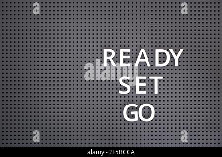 Wörter bereit, setzen, gehen buchstabiert heraus mit weißen Buchstaben auf grauem Pegboard Stockfoto