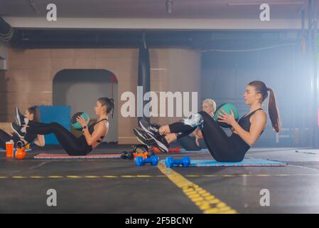 Seitenansicht der schönen jungen Frauen Ausübung russischen Twist mit Medizinball aus sitzender Position für starke bauchmuskeln Stockfoto