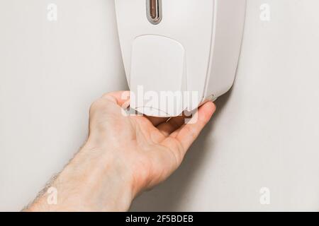 Der Mann hob seine Hand zum Seifenspender, aus der Nähe. Stockfoto