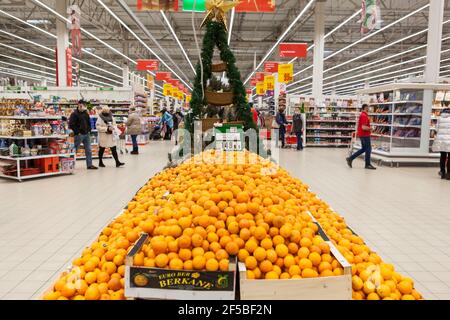 St. Petersburg, Russland-circa Dez, 2020: Der Verkauf von Mandarinen findet vor Neujahr im Auchan-Supermarkt statt. Der Stand ist mit Weihnachtsbaum geschmückt. It Stockfoto