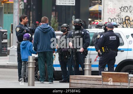 Eine Gruppe von NYPD Polizisten in Gesichtsmasken und tragen Halbautomatische Gewehre sprechen mit Fußgängern am Times Square Stockfoto