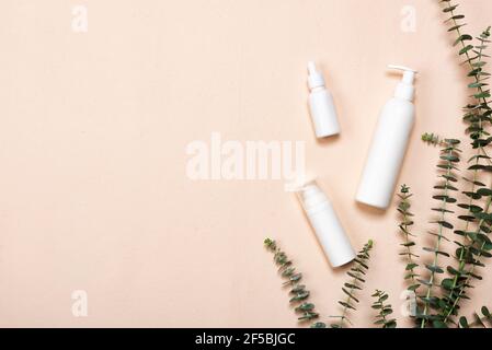 Flaschen von Essenz oder Serum mit natürlichen Eukalyptusblättern auf beigem Hintergrund. Naturkosmetik und Spa Flat Lay Stockfoto