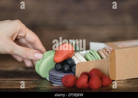 Die Hand der Frau legt französische Makronen-Kuchen aus Stockfoto