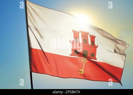 Gibraltar Flagge winkt auf dem Wind vor der Sonne Stockfoto