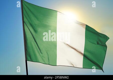 Nigeria Flagge winkt auf dem Wind vor der Sonne Stockfoto